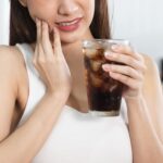 冷たい飲み物で歯がしみている女性